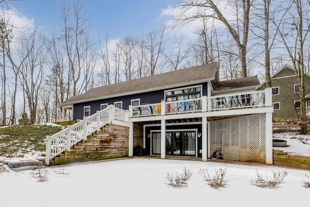 snow covered back of property featuring a deck