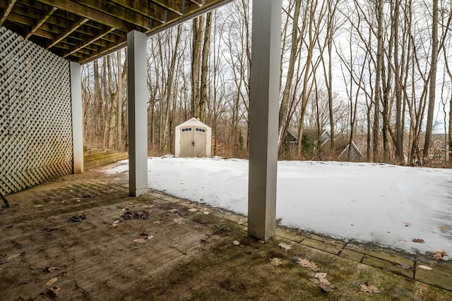 snow covered patio featuring a shed