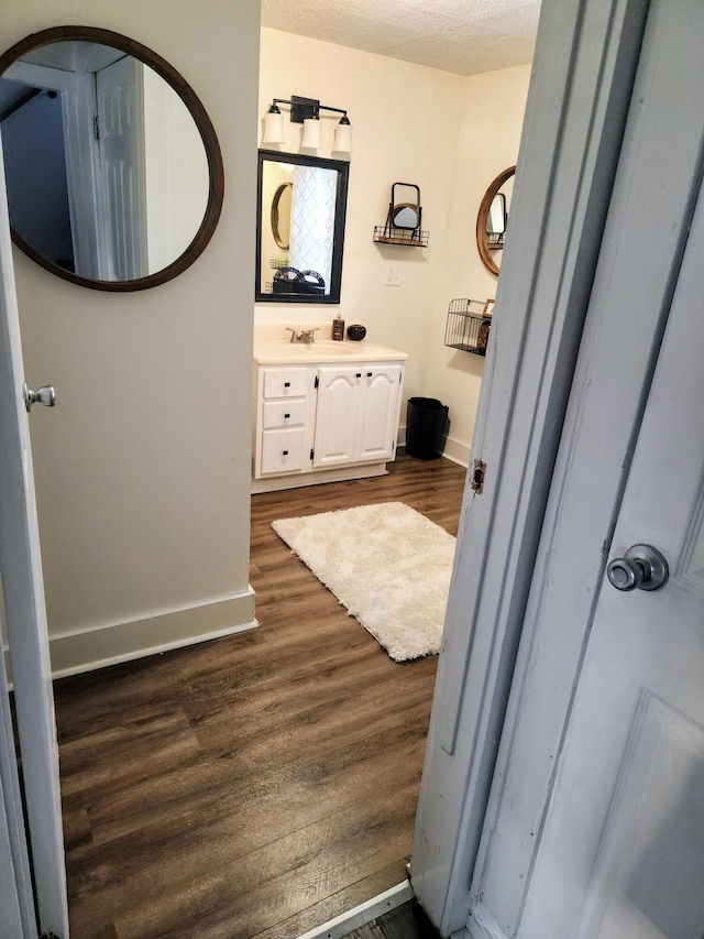 bathroom featuring wood-type flooring, vanity, and a textured ceiling