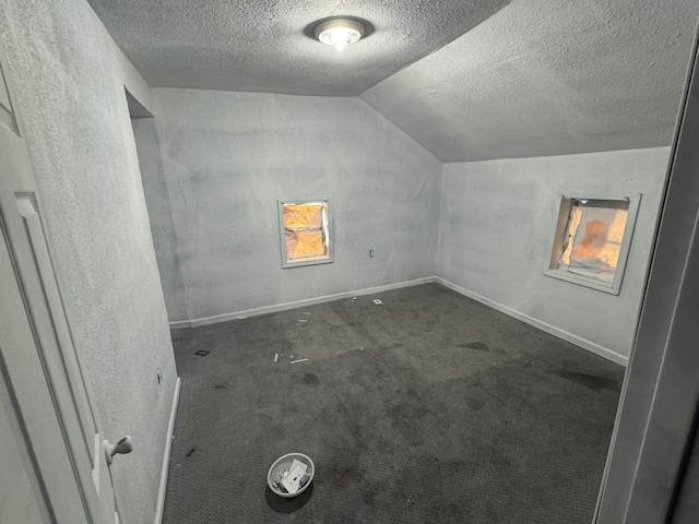 bonus room with lofted ceiling, a textured ceiling, and dark colored carpet