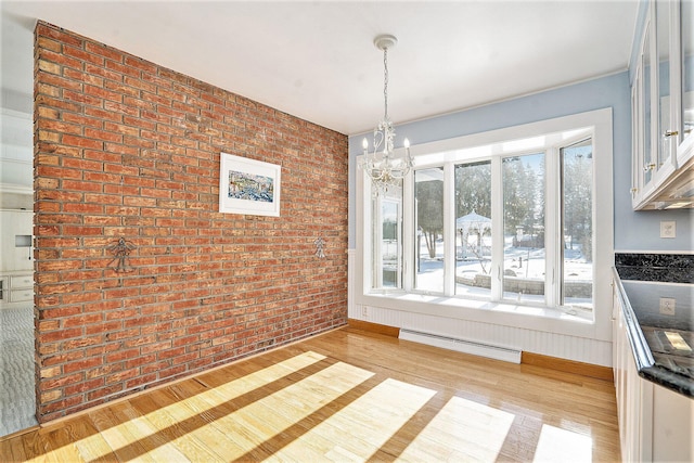 unfurnished dining area with a notable chandelier, light wood-type flooring, a baseboard radiator, and brick wall