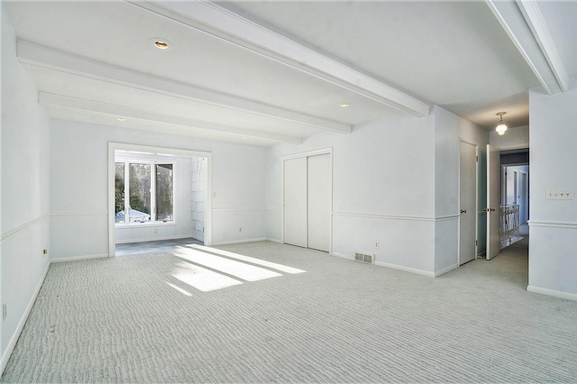 unfurnished room featuring light colored carpet and beam ceiling