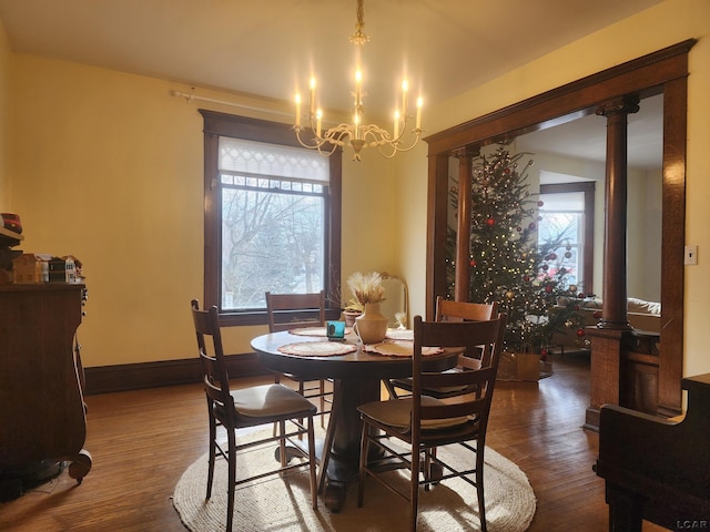 dining room with ornate columns, dark hardwood / wood-style floors, and an inviting chandelier