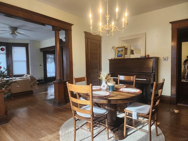 dining space with ornate columns, wood-type flooring, and ceiling fan with notable chandelier