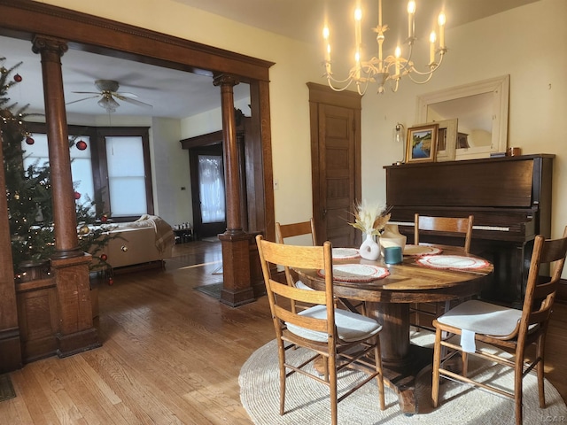 dining area with hardwood / wood-style flooring, ceiling fan with notable chandelier, and ornate columns