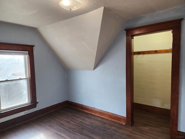 additional living space with dark hardwood / wood-style floors, vaulted ceiling, and a textured ceiling