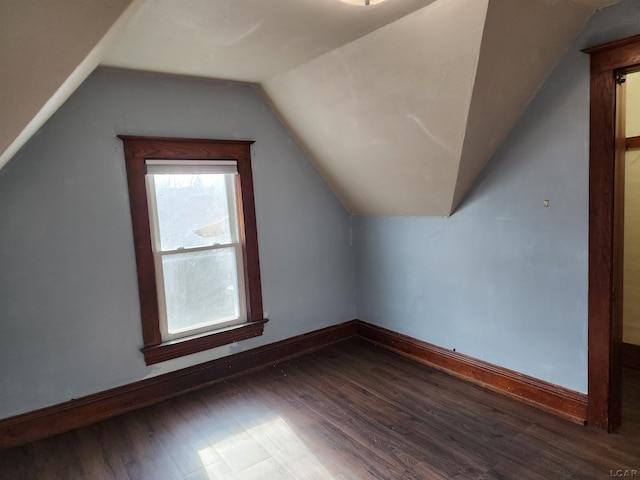 additional living space featuring dark wood-type flooring and vaulted ceiling