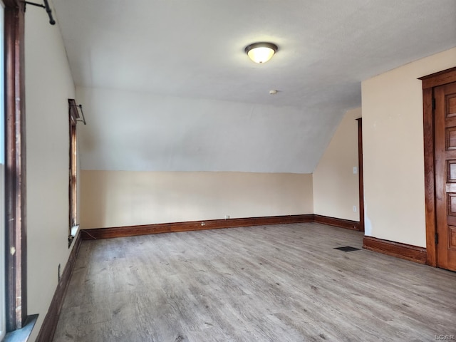 additional living space with lofted ceiling and light hardwood / wood-style flooring