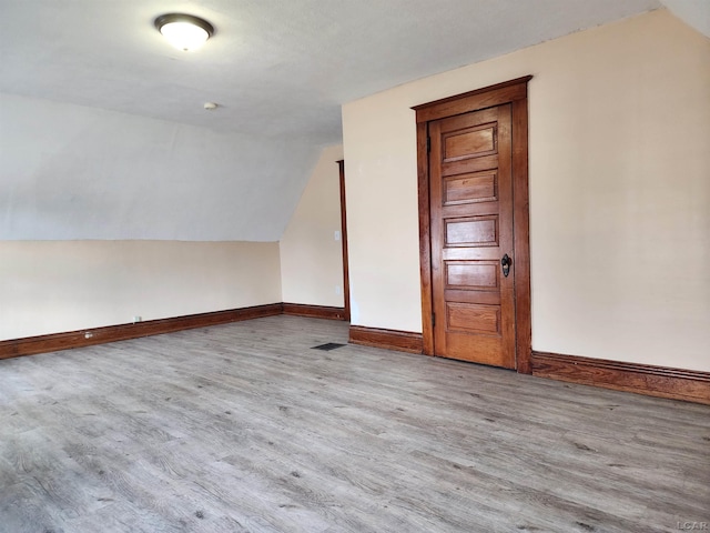 bonus room with vaulted ceiling and light wood-type flooring