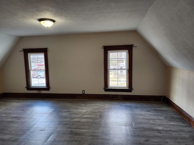 additional living space featuring vaulted ceiling, dark hardwood / wood-style floors, a wealth of natural light, and a textured ceiling