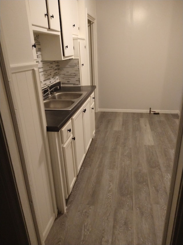 kitchen featuring sink, backsplash, dark wood-type flooring, and white cabinets