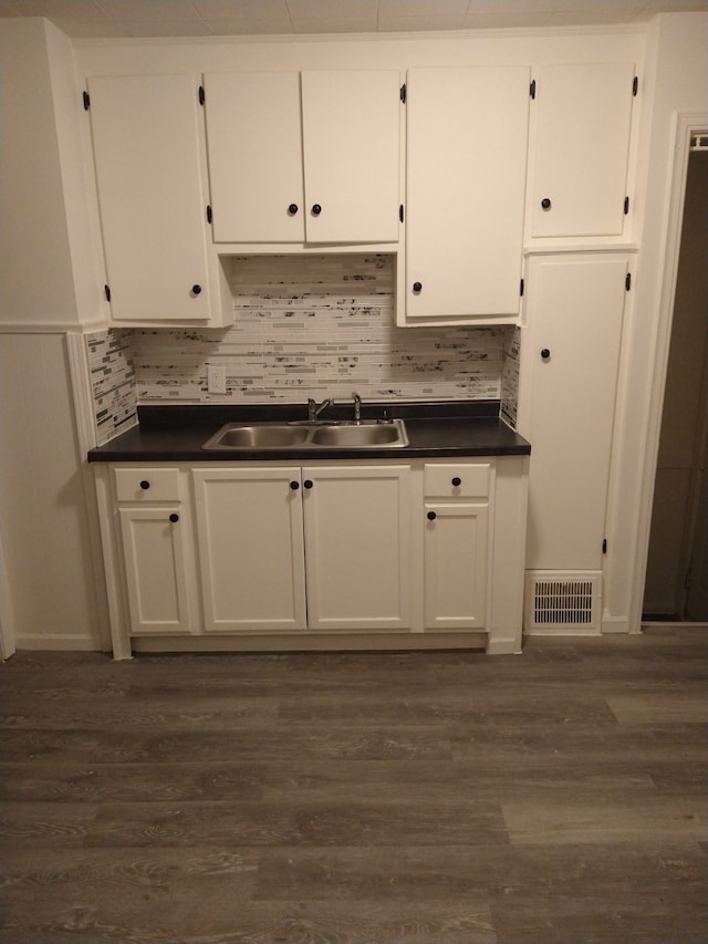 kitchen featuring dark hardwood / wood-style flooring, sink, tasteful backsplash, and white cabinets