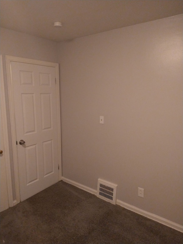 spare room featuring dark carpet