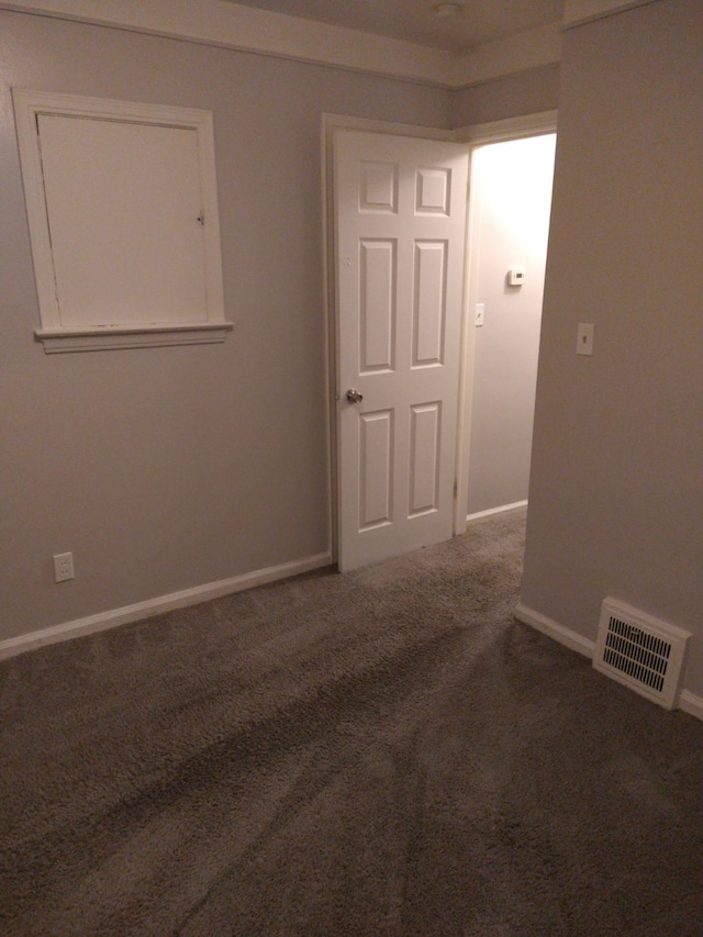 spare room with dark carpet