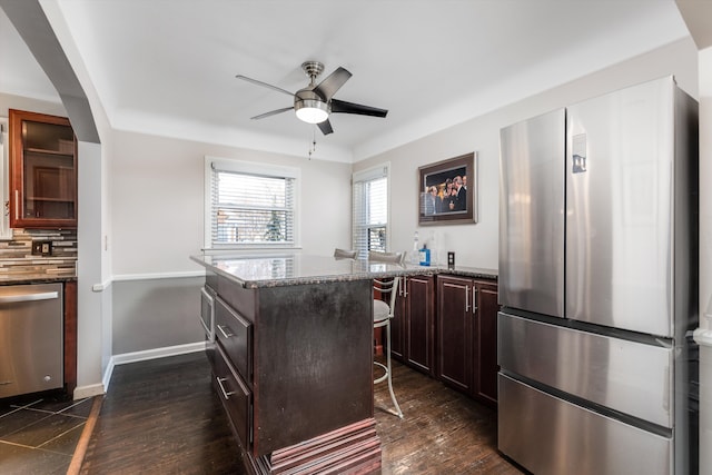 kitchen featuring appliances with stainless steel finishes, a kitchen breakfast bar, a center island, and stone countertops