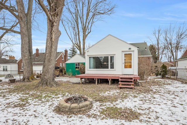 snow covered rear of property featuring a wooden deck and a fire pit