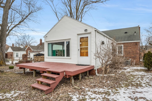 snow covered rear of property with a wooden deck