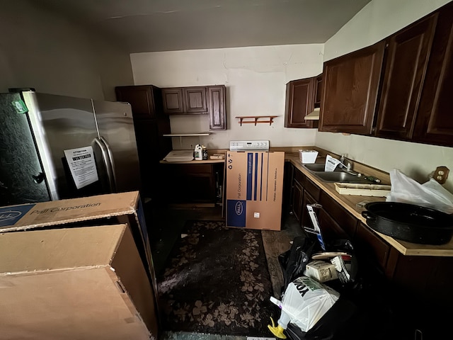 kitchen featuring dark brown cabinetry, sink, and stainless steel refrigerator