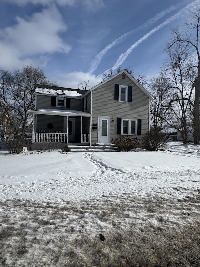 snow covered back of property featuring a porch