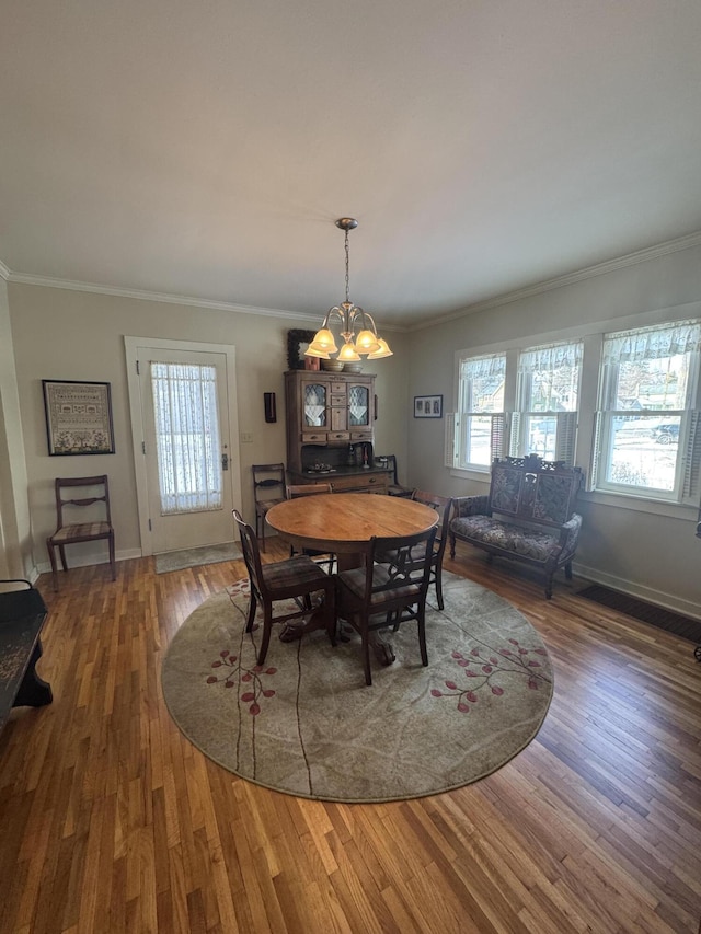 dining room featuring crown molding, hardwood / wood-style floors, and a notable chandelier