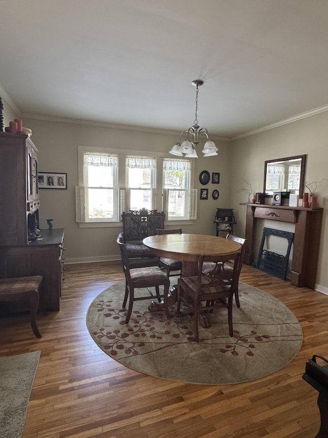 dining space with dark wood-type flooring, ornamental molding, and a chandelier