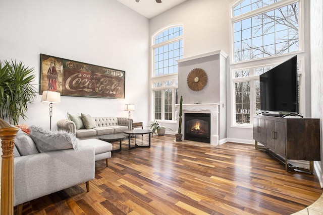 living room featuring a high end fireplace, dark wood-type flooring, and a towering ceiling