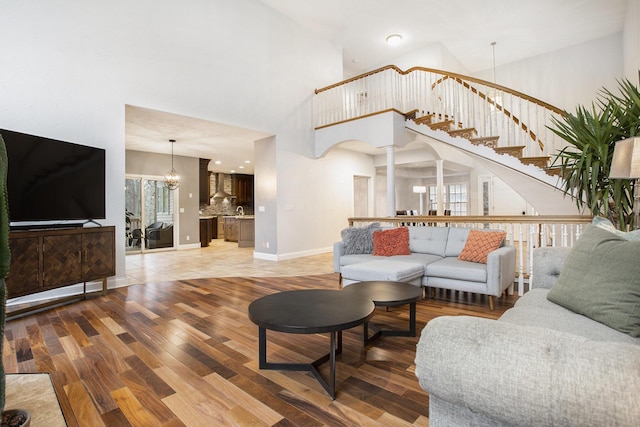 living room featuring a towering ceiling, a chandelier, and hardwood / wood-style floors