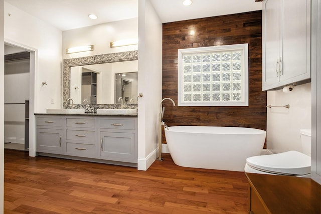 bathroom featuring vanity, a tub to relax in, hardwood / wood-style flooring, and wood walls