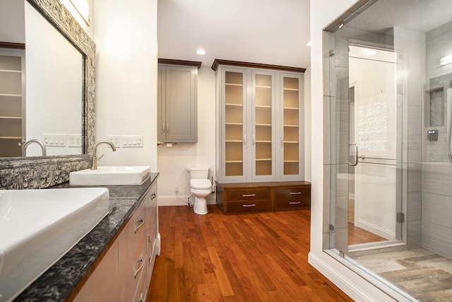 bathroom with hardwood / wood-style flooring, vanity, toilet, and walk in shower