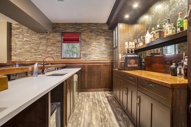 bar with wood-type flooring, sink, and dark brown cabinets