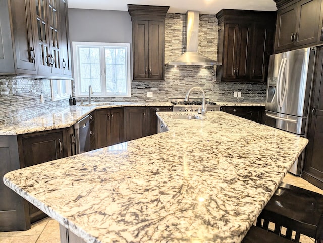 kitchen featuring stainless steel appliances, light stone countertops, and wall chimney range hood