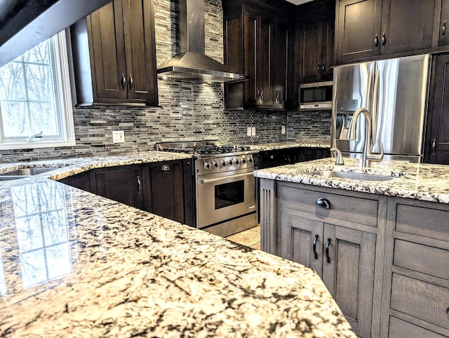 kitchen featuring sink, stainless steel appliances, light stone countertops, dark brown cabinets, and wall chimney exhaust hood