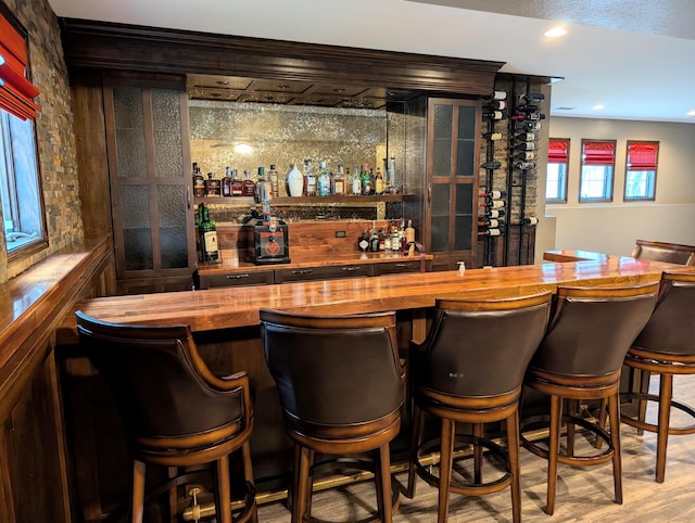 bar with butcher block countertops and light wood-type flooring