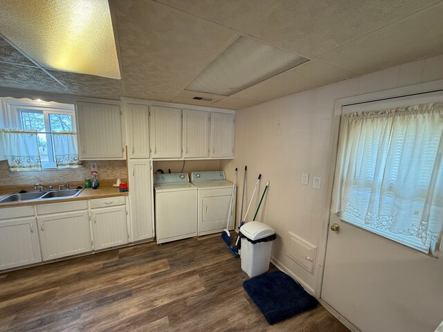 clothes washing area with washing machine and dryer, cabinets, dark wood-type flooring, and sink