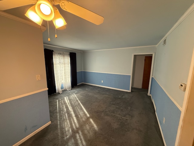 unfurnished room featuring ceiling fan, dark colored carpet, and crown molding