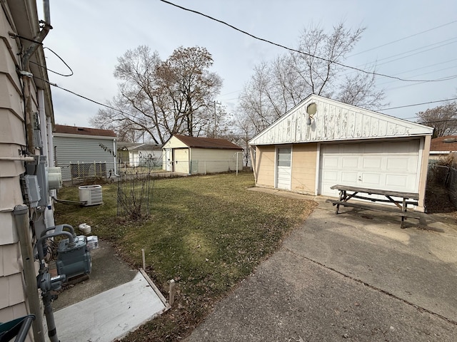 view of yard featuring an outbuilding, a garage, and central air condition unit