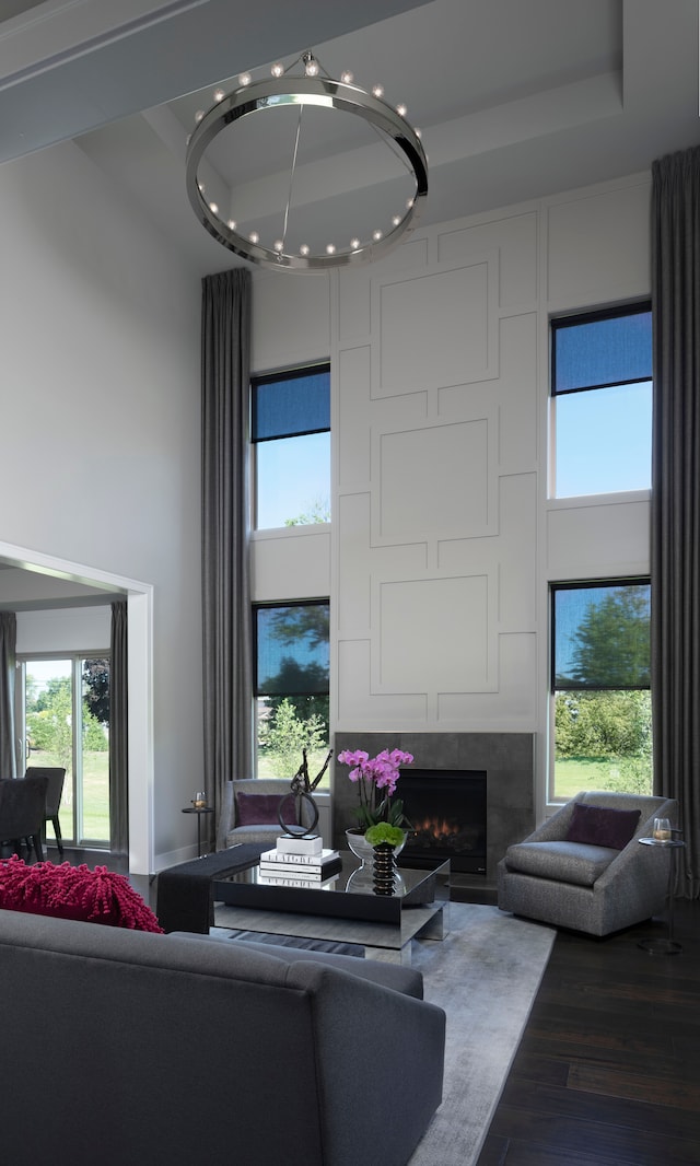 living room featuring a towering ceiling, a tray ceiling, a fireplace, and hardwood / wood-style floors