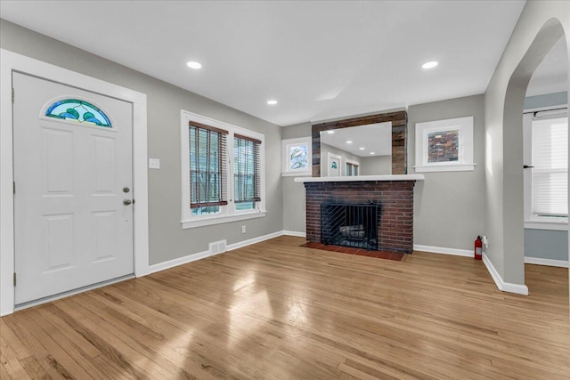 entrance foyer featuring a brick fireplace and light hardwood / wood-style floors