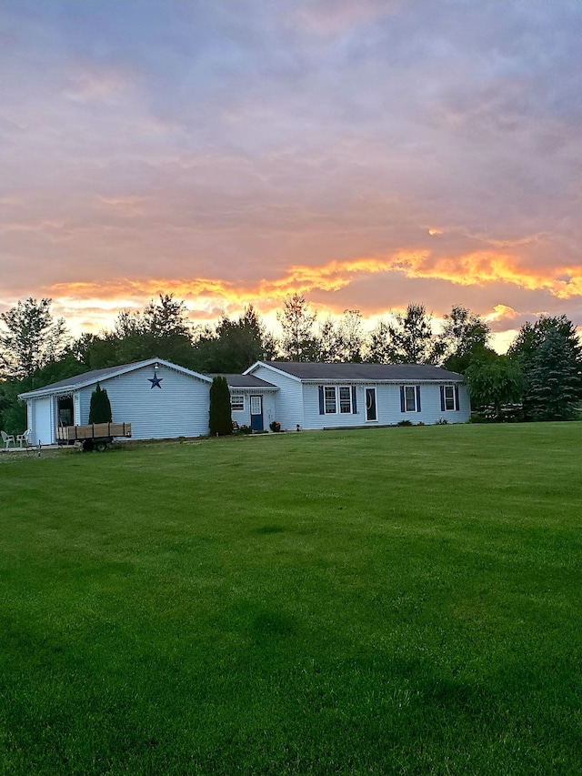 back house at dusk featuring a lawn