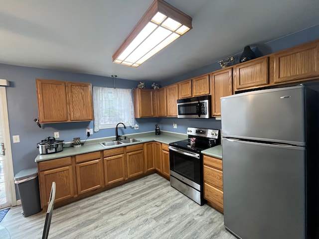 kitchen featuring pendant lighting, stainless steel appliances, sink, and light hardwood / wood-style flooring