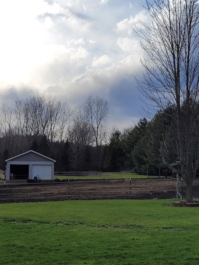 view of yard with an outbuilding, a garage, and a rural view