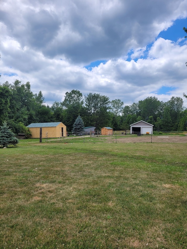 view of yard featuring a garage, an outbuilding, and a rural view