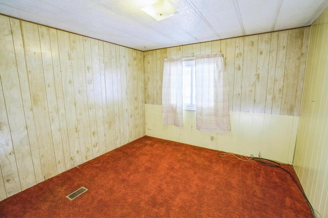 unfurnished room with carpet and wooden walls