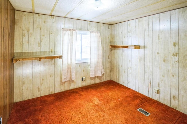 spare room with carpet and wood walls