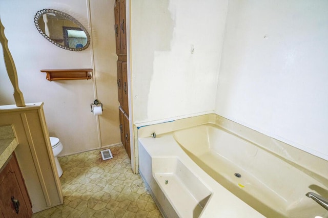 bathroom with vanity, a bath, and toilet
