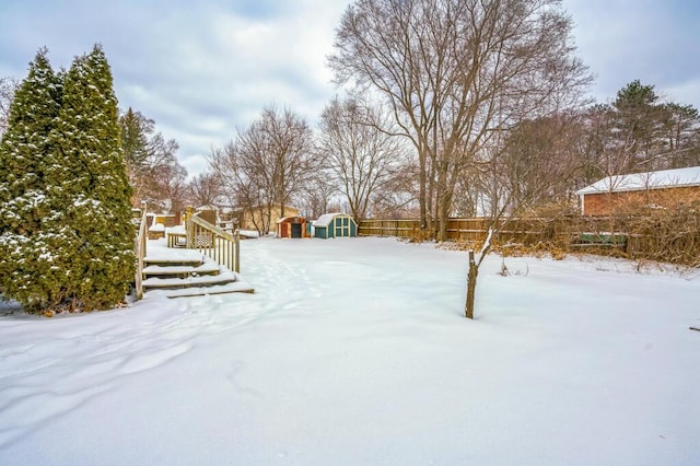yard layered in snow featuring a storage unit