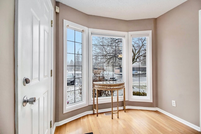 doorway with a textured ceiling and light hardwood / wood-style flooring