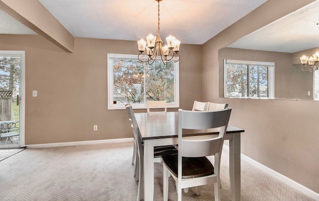 dining space featuring a healthy amount of sunlight, carpet flooring, and a chandelier