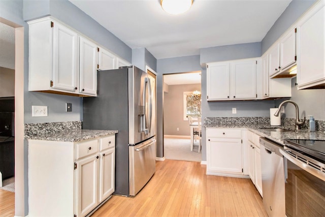 kitchen with appliances with stainless steel finishes, sink, white cabinets, and light wood-type flooring