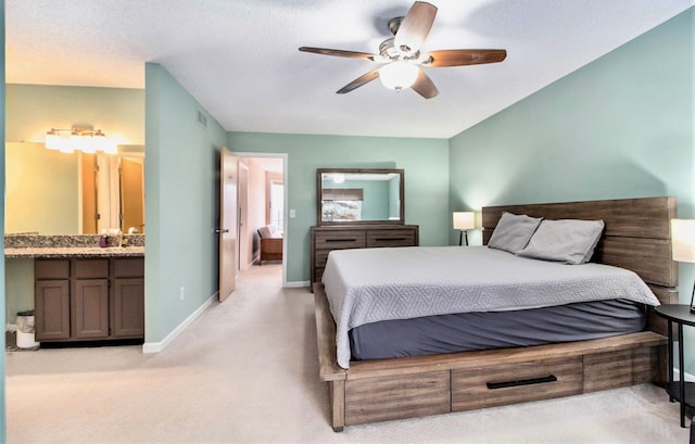 bedroom with sink, light colored carpet, ceiling fan, and ensuite bathroom